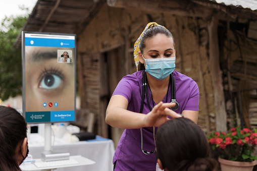 Enfermera latina con dispositivo inalámbrico que revisa el ojo del paciente photo
