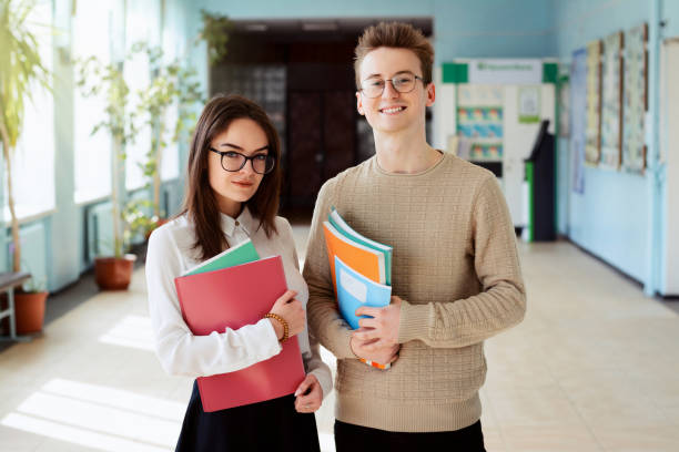 istock Male and female students standing in university hall during break, communicating and looking to the camera 1326647024