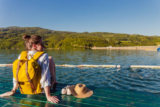 istock Woman with backpack relaxing by the lake and looking at view 1326647140