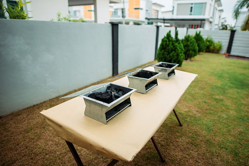wide shot of three sets of barbecue grill preparing in front yard of house