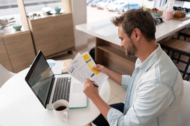 istock Man at home paying bills online on his laptop computer 1326651863