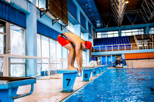 istock Man preparing for a jump in an indoor pool 1326651868