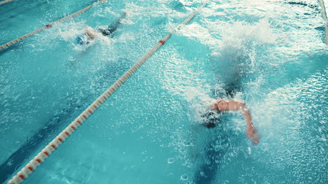 Swim Race: Two Professional Swimmers in Swimming Pool, Stronger and Faster Winner Decided. Athletes Compete the Best Wins Championship. Slow Motion with Stylish Colors, Close-up Aerial Tracking View