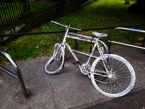 Damaged white-painted old bicycle, placed at the Middle Meadows Walk, near the entrance to the Meadows Park, Edinburgh, Scotland