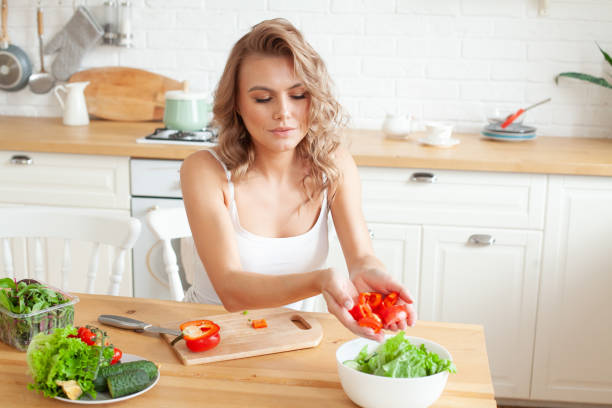 istock Happy young woman making a salad at the kitchen 1326659895