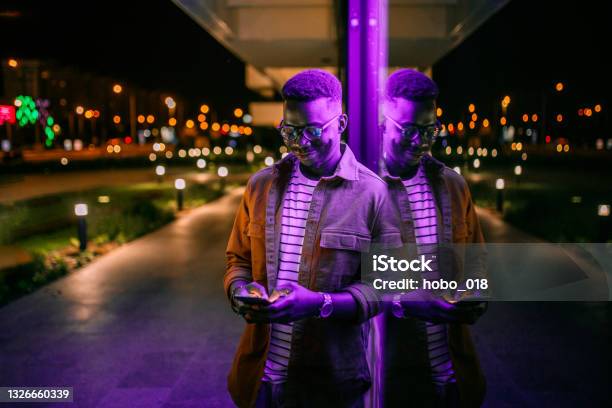 Using Phone In A Front Of Neon Lights On The Street Stock Photo - Download Image Now