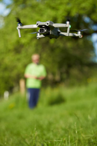 Nürtingen, Germany - May 29, 2021: Gray drone flies over the green meadow. human pilot controls the flying object (uas). Newest multicopter from the manufacturer dji (air 2s).