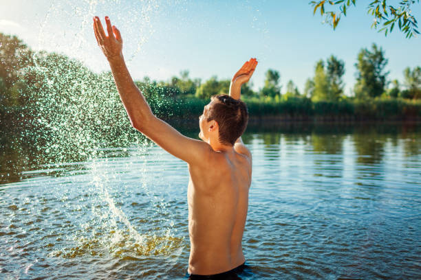 istock Young man enjoys playing in water and making splash. Having fun during summer vacation 1326662906