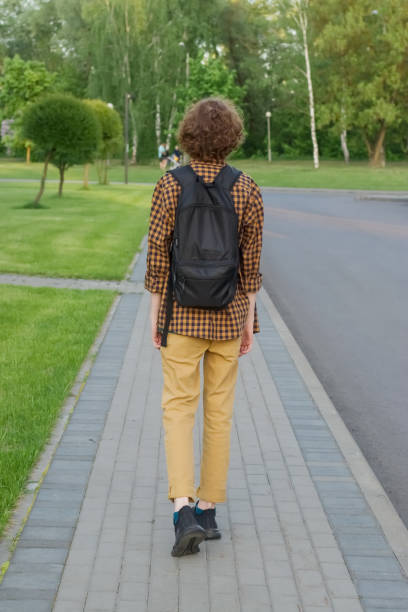 istock A person with a backpack is walking on the sidewalk. Vertical photo. 1326664909