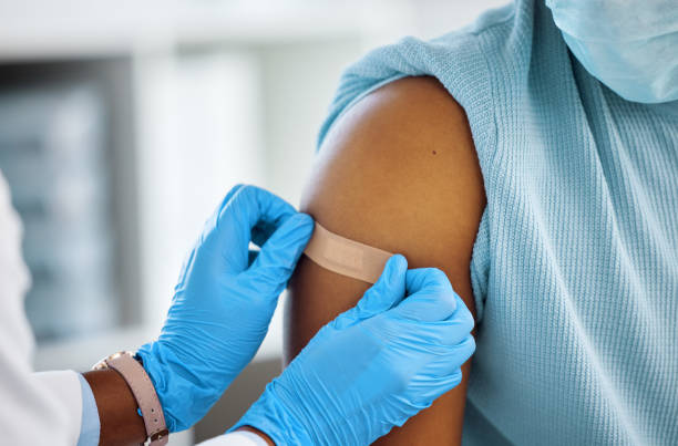 Shot of a doctor applying a plaster to her patients arm Just leave this on for an hour pneumonia photos stock pictures, royalty-free photos & images