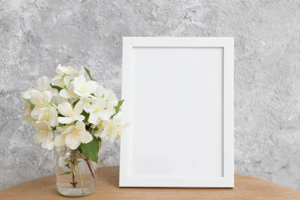 istock Mock up empty white frame on a round table with jasmine flowers on a gray background. Place your text or image 1326667549