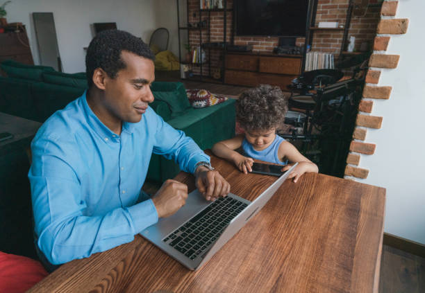 istock Father taking care of son while working on laptop  at home 1326670917