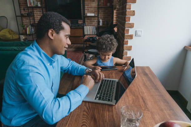 istock Father taking care of son while working on laptop  at home 1326670925
