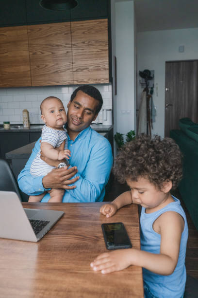 istock Father taking care of son while working on laptop  at home 1326670935