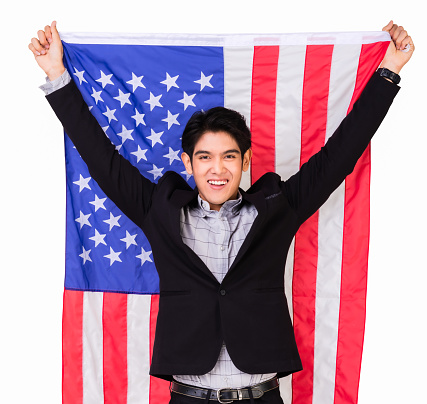 Happy handsome young man with standing hands hold American flag in studio shoot on white background. USA celebrate 4th of July. Independence day concept.