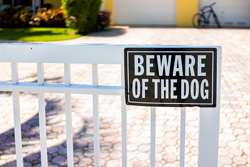 Tenga cuidado con el letrero del perro en la barandilla de la puerta de la cerca blanca en la casa residencial del vecindario en Hollywood, Florida Broward County North Miami Beach photo