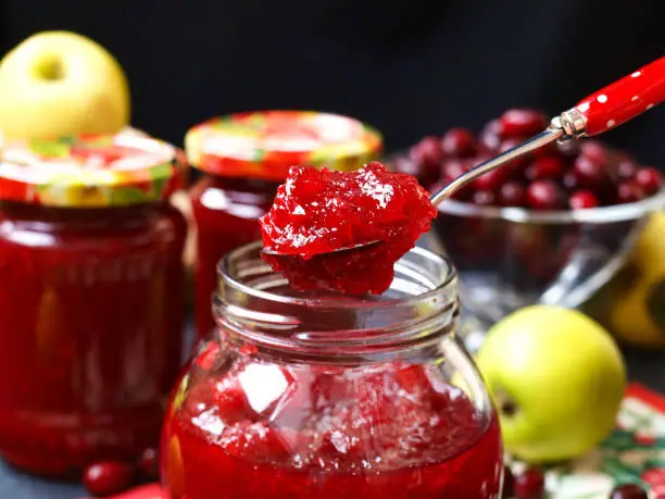 Homemade jam of dogwoods and apples is located in the jars on the table, one jar is open, Preparation of jam for the winter