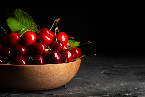 Close-up Cherries in wooden Bowl with water drops on rustic table. Healthy Food Background