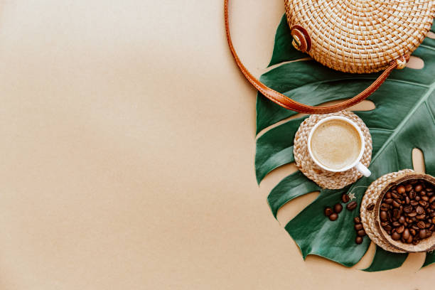Monstera leaf ,coffee cup and Ratan bag on brown background. Copy space. summer minimal background flat lay, view from top