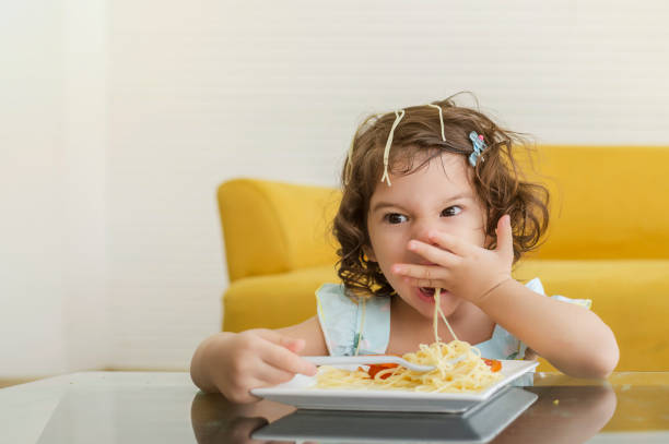 istock Little child enjoys eating spagetti by herself. 1326687398