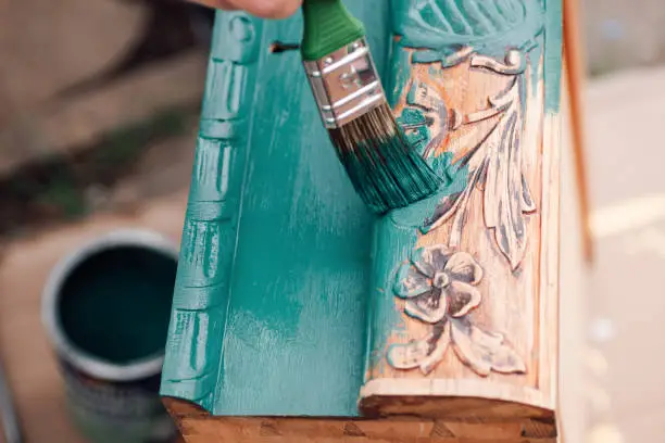 the process of painting a wooden dresser drawer or table with a floral pattern outdoors, an eco-friendly re-use business.