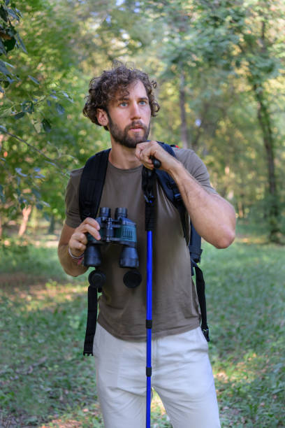 istock Young Man is Hiking in Forest in Nature and Using Binoculars. 1326700119