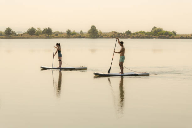 istock Man and woman stand up paddleboarding 1326702932