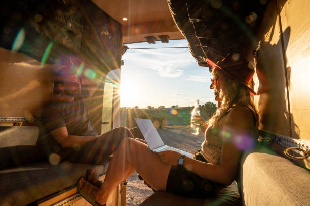 istock Couple Relaxing, Checking Messages On The Computer In Their Camper Van As The Sun Is Setting 1326704645