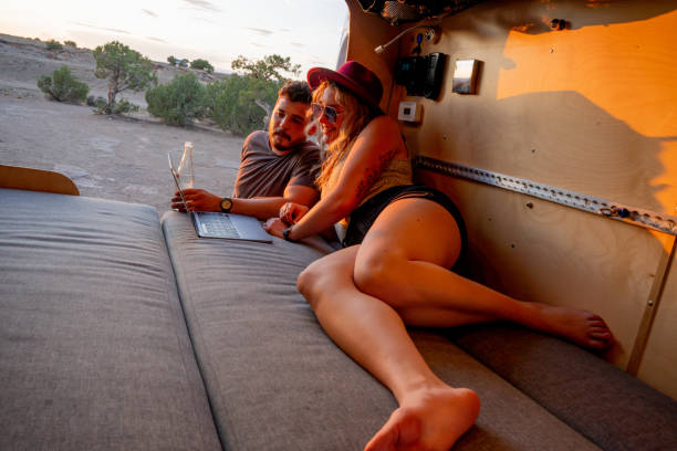 istock Couple Talking And Checking Messages On The Computer In Their Camper Van As The Sun Is Setting 1326704696