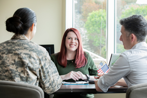 Mature female financial planner speaking to military couple.