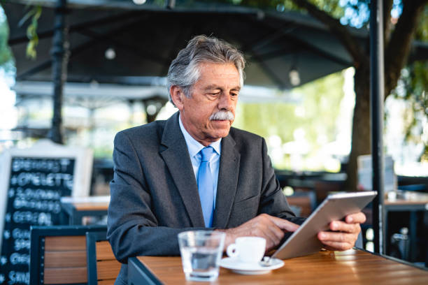 istock Senior Businessman Using Digital Tablet at Outdoor Cafe 1326709150