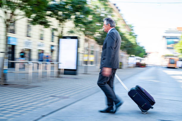istock Senior Executive Pulling Wheeled Luggage on Business Trip 1326709160