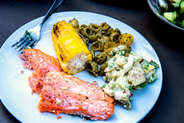 Sockeye salmon meal on the plate, with corn and potato salad ready to eat