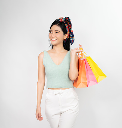 Photo of a young Thai lady with shopping bags on white background.