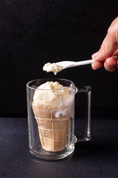 istock A woman's hand holds a spoon with ice cream. Dark photo. 1326722257