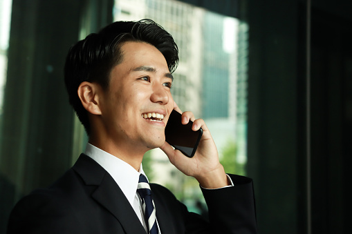 Confident Asian businessman in a suit taking a phone call in the office
