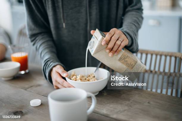 Cropped Shot Of Young Asian Mother Preparing Healthy Breakfast Pouring Milk Over Cereals On The Kitchen Counter Healthy Eating Lifestyle Stock Photo - Download Image Now