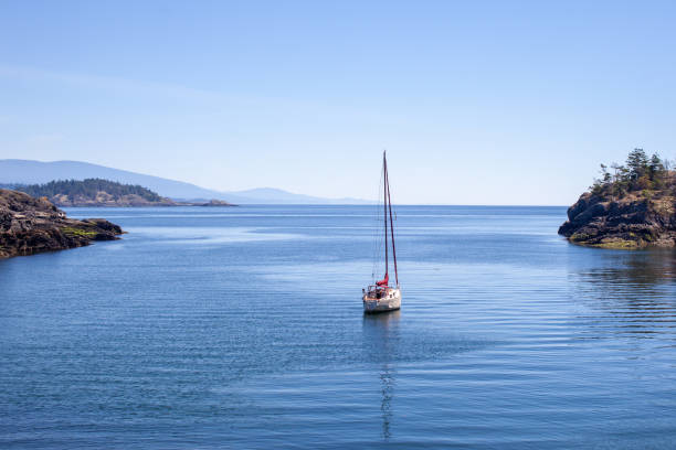 A sailboat is anchored (moored) in a small cove on the southern end of Thormanby Island, on the Sunshine Coast. A popular spot for summer cruising.