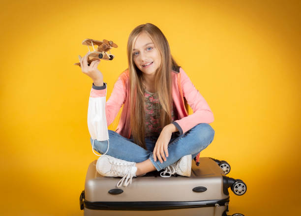petite fille avec une valise et un avion jouet triste de ne pas pouvoir voyager - elementary age focus on foreground indoors studio shot photos et images de collection