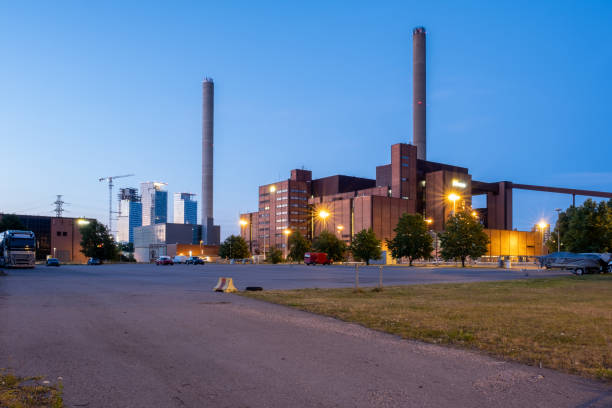 istock An old power plant with two smoke stacks. Modern skyscrapers in the background. 1326744603
