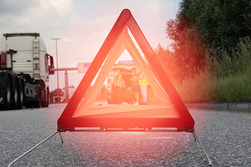 Warning triangle set up near the motorway after an accident between an SUV and a truck