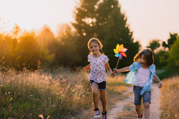 happy kids s’amusant avec pinwheel dans la nature. enfants qui courent - moulinet jouet photos et images de collection