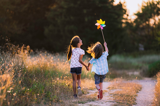 Happy Kids having fun with pinwheel in the nature. Running kids