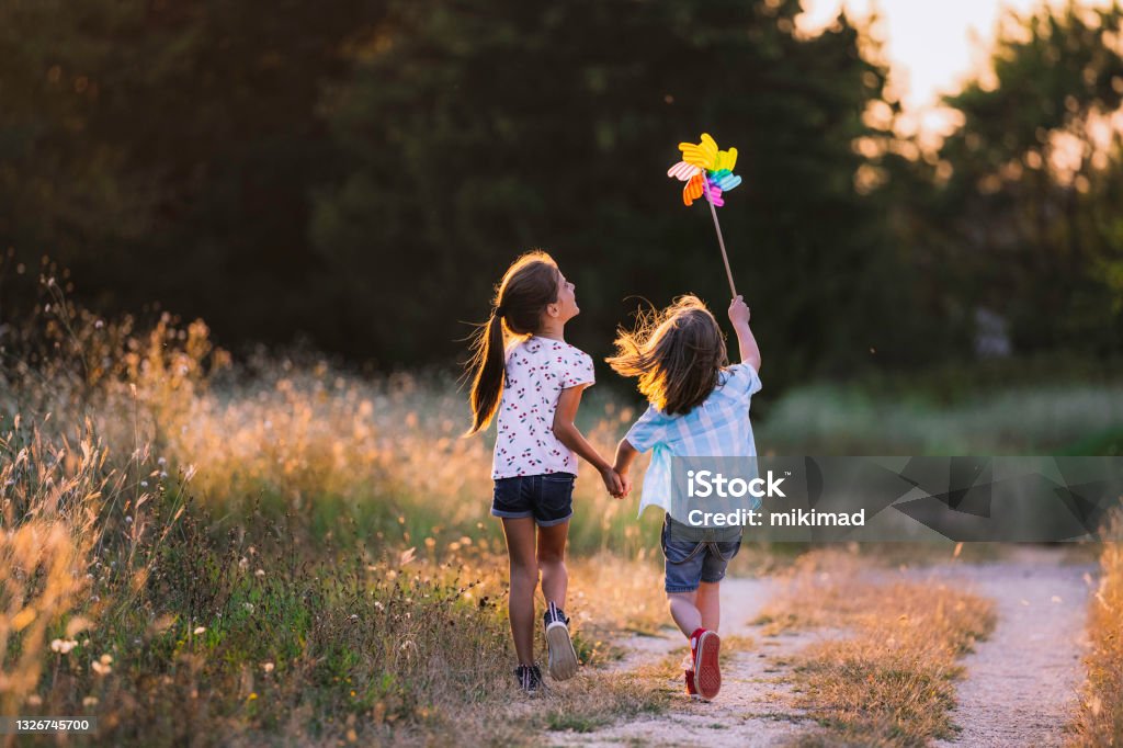 Happy Kids having fun with pinwheel in the nature. Running kids Child Stock Photo