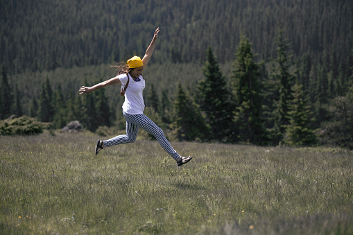 A beautiful woman makes a spectacular jump in a beautiful mountain landscape.
