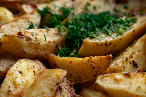 Aromatic baked potato wedges with fresh dill herbs.  Homemade rustic dish, delicious hearty food close up stock photo