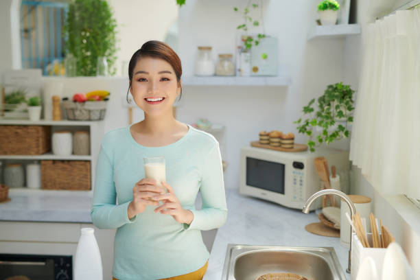 istock Happy young girl drink a milk for breakfast in kitchen conner. 1326748332
