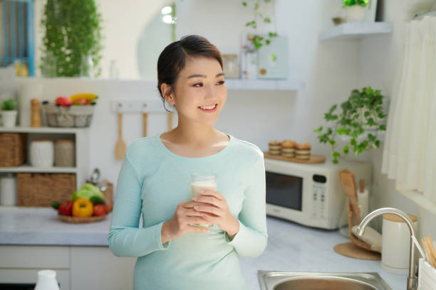 istock Beautiful woman drinking milk in kitchen at home 1326748364