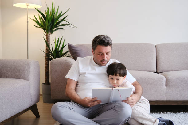istock Father reading book to son on sofa 1326748377