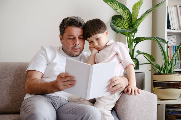 istock Father reading book to son on sofa 1326748409